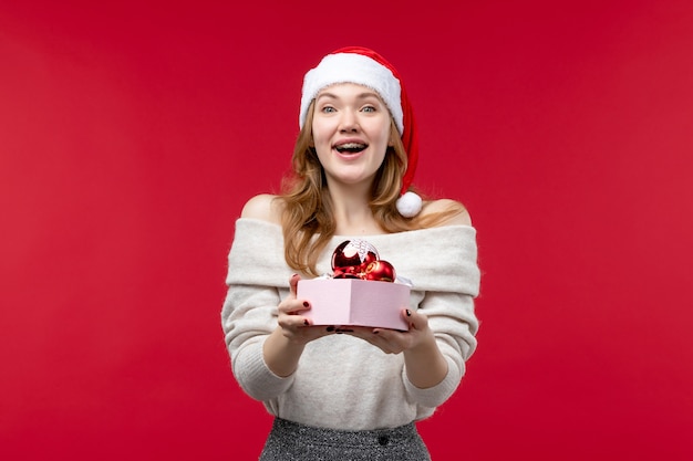 Vue de face d'une jolie femme tenant des jouets de Noël sur le rouge