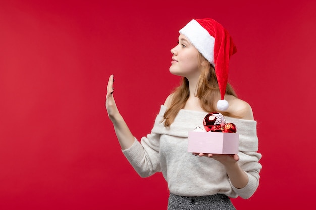 Photo gratuite vue de face d'une jolie femme tenant des jouets de noël sur le rouge