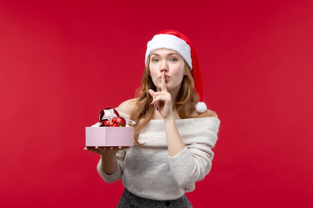 Vue de face d'une jolie femme tenant des jouets de Noël sur le rouge