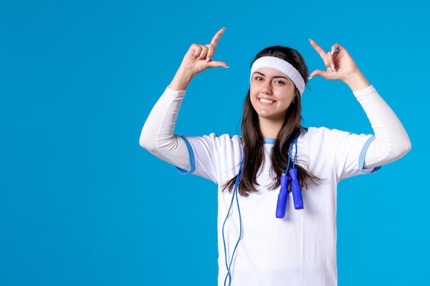 Vue de face jolie femme en vêtements de sport avec corde à sauter sur bleu