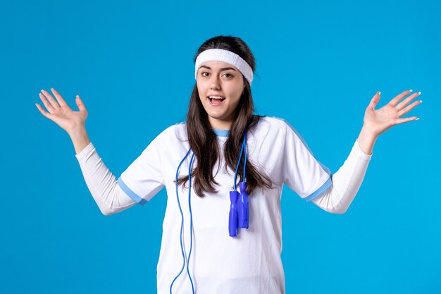 Vue de face jolie femme en vêtements de sport avec corde à sauter sur bleu