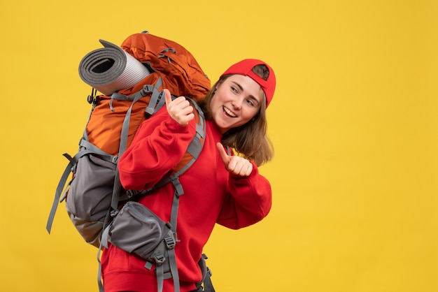 Vue de face jolie femme voyageur avec bonnet rouge pointant sur sac à dos