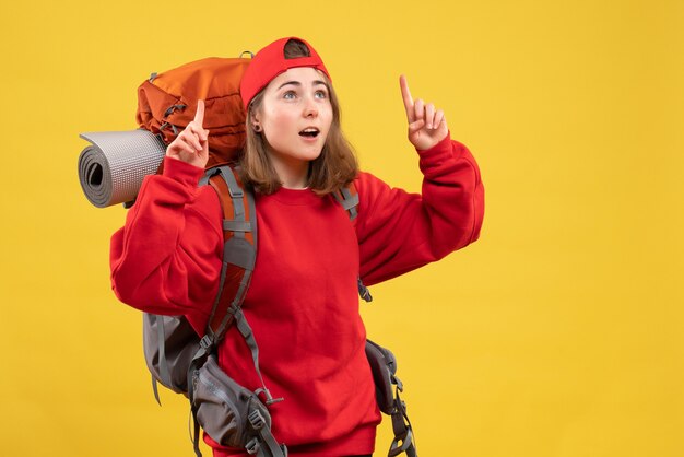 Vue de face jolie femme voyageur avec sac à dos pointant les doigts vers le haut