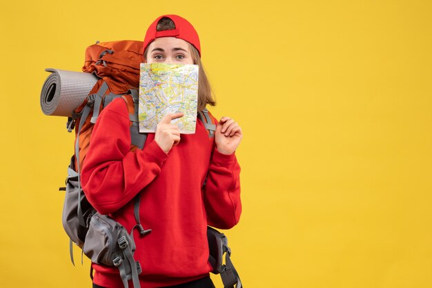 Vue de face jolie femme voyageur avec sac à dos tenant une carte de voyage à son visage