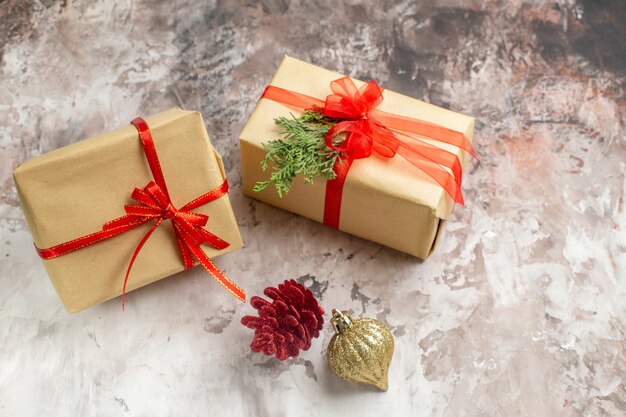 Vue de face de jolis cadeaux de Noël attachés avec des arcs rouges sur fond clair