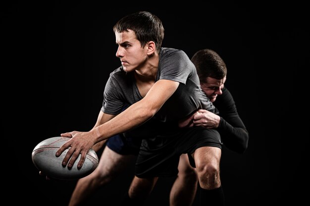 Vue de face des joueurs de rugby masculins avec ballon