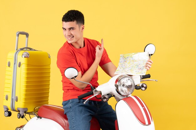 Vue de face joyeux jeune homme sur la carte de tenue de cyclomoteur