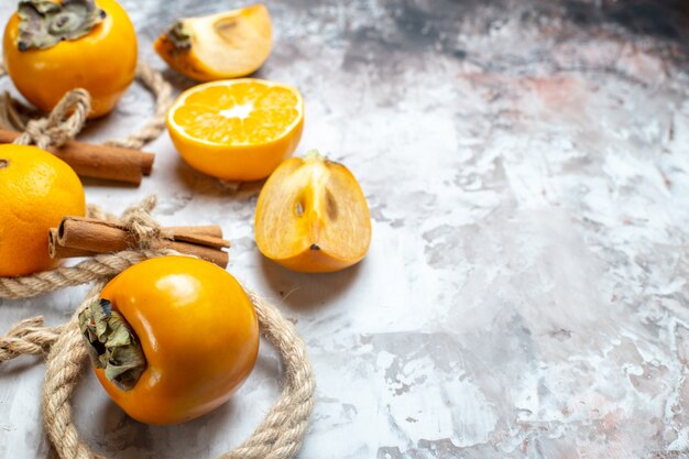 Vue de face des kakis frais à l'orange et à la cannelle sur la table lumineuse