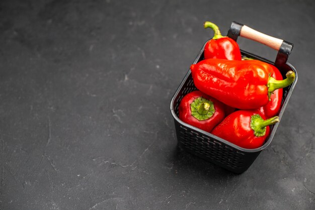 Vue de face de légumes épicés de poivrons rouges sur fond sombre