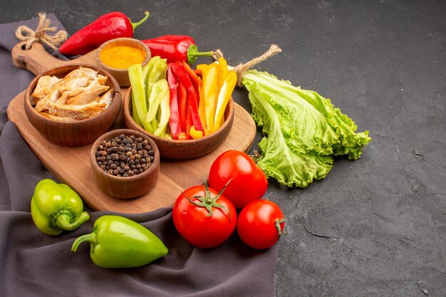 Vue de face des légumes frais mûrs avec des assaisonnements sur un espace sombre