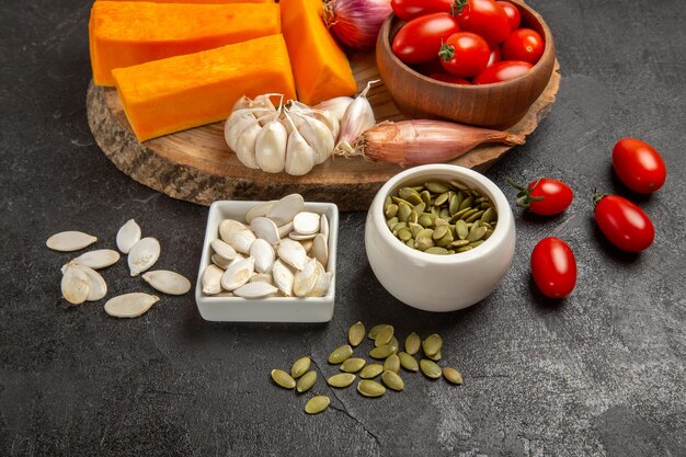 Vue de face des légumes frais avec des tranches de citrouille et de l'ail sur fond gris couleur des graines salade mûre fraîche