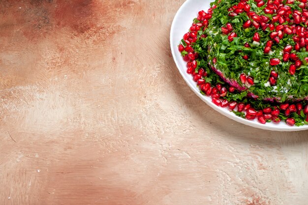 Vue de face des légumes verts frais avec des grenades pelées sur la table lumineuse couleur verte des fruits