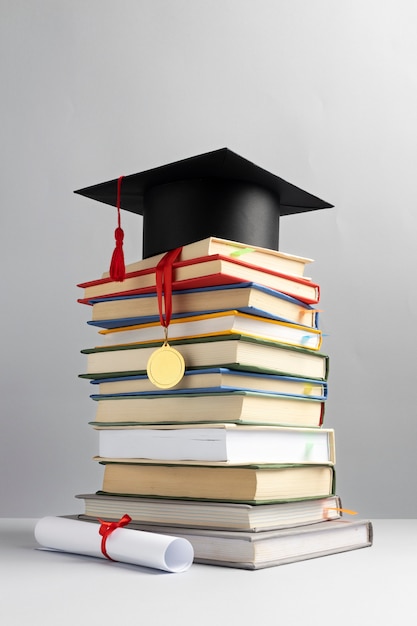 Photo gratuite vue de face de livres empilés, d'un chapeau de graduation et d'un diplôme pour la journée de l'éducation