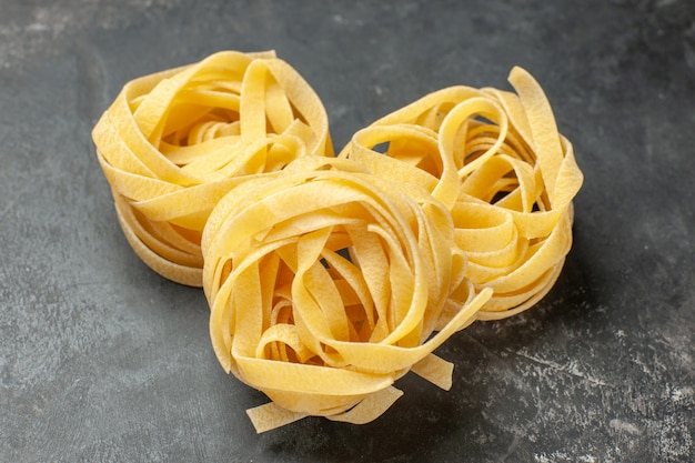 Vue de face de longs morceaux de pâte roulés sur fond gris clair pâte repas nourriture pâtes cuisine