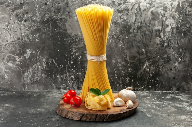 Vue de face de longues pâtes italiennes aux tomates rouges et à l'ail sur un repas de photo de cuisine de pâte de couleur alimentaire gris clair