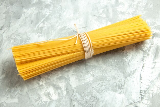 Vue de face de longues pâtes italiennes crues attachées sur de la lumière photo couleur alimentaire beaucoup de pâte