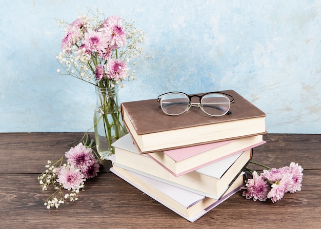 Vue de face des lunettes sur le livre et des fleurs sur une table en bois