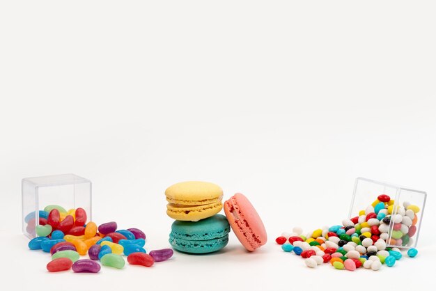 Une vue de face macarons français avec des bonbons colorés et des marmelades sur blanc, couleur sucre sucré