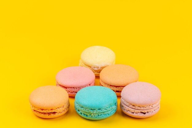 Une vue de face macarons français colorés délicieux sur jaune, couleur biscuit gâteau