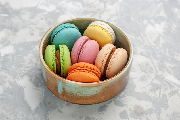 Vue de face macarons français de couleur délicieux petits gâteaux sur une surface blanche