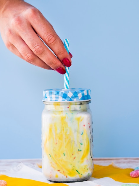 Photo gratuite vue de face de la main et du milkshake sur fond bleu