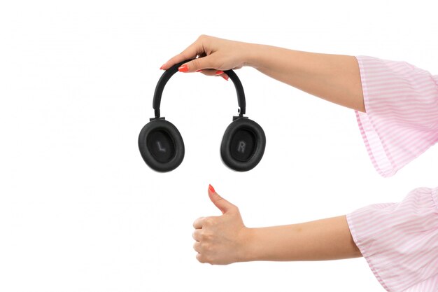 Une vue de face main féminine tenant des écouteurs noirs comme signe sur le blanc