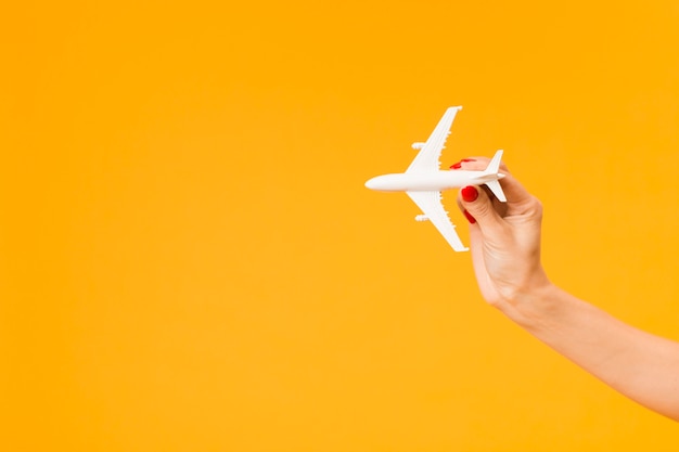 Vue de face de la main tenant la figurine d'avion avec copie espace