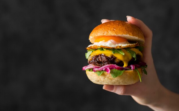 Vue de face main tenant un hamburger avec copie-espace
