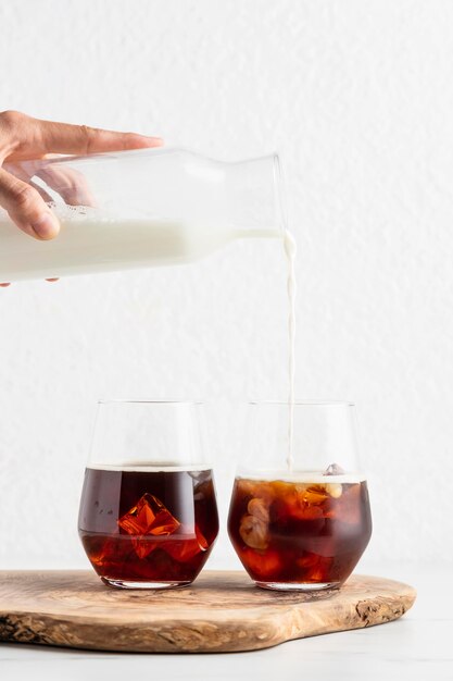 Vue de face de la main, verser le lait dans des verres à café