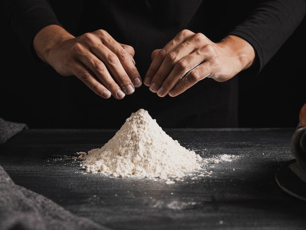 Vue de face des mains de boulanger mélangeant la farine