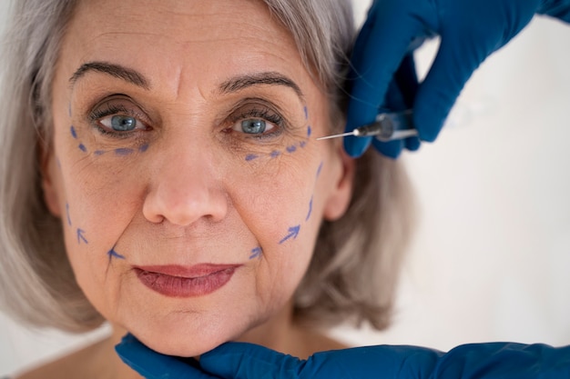 Vue de face mains s'appuyant sur le visage d'une femme âgée