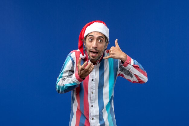 Vue de face mâle régulier avec bonnet de noël rouge sur bureau bleu vacances santa émotion