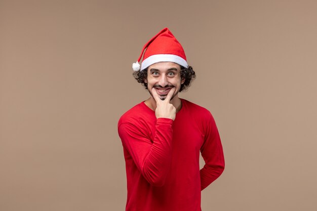 Vue de face mâle en rouge souriant sur fond marron vacances émotion noël