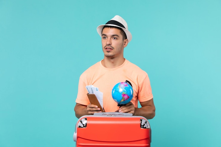 Photo gratuit vue de face mâle en vacances tenant un petit globe et des billets sur bleu