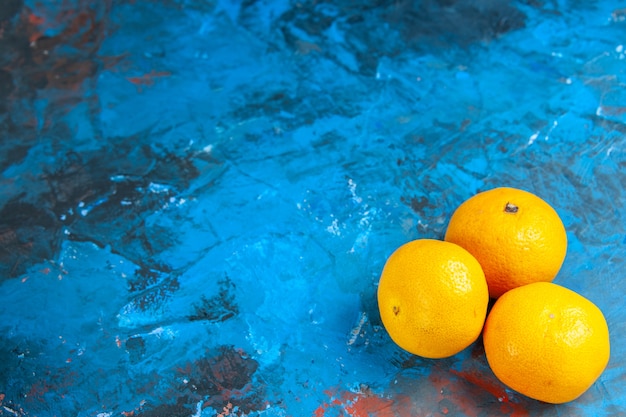 Vue de face des mandarines fraîches sur un bureau bleu