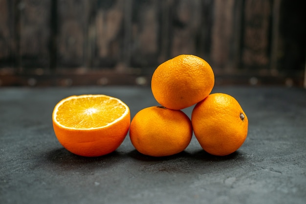 Vue de face des mandarines fraîches coupées en orange sur fond sombre