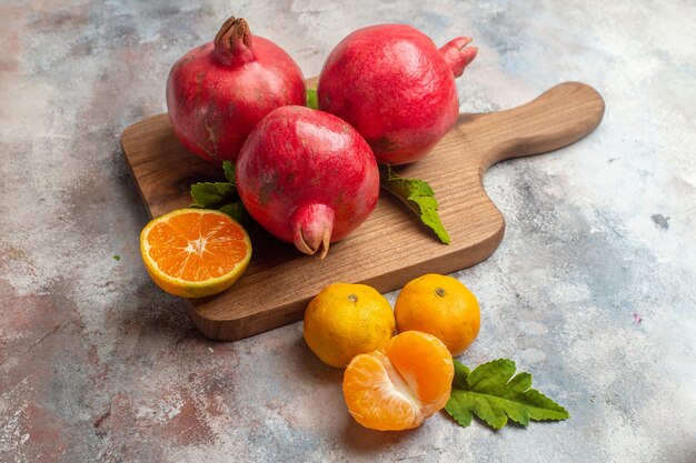 Vue de face mandarines fraîches avec grenades rouges sur fond clair jus couleur goût vitamine fruit arbre photo exotique