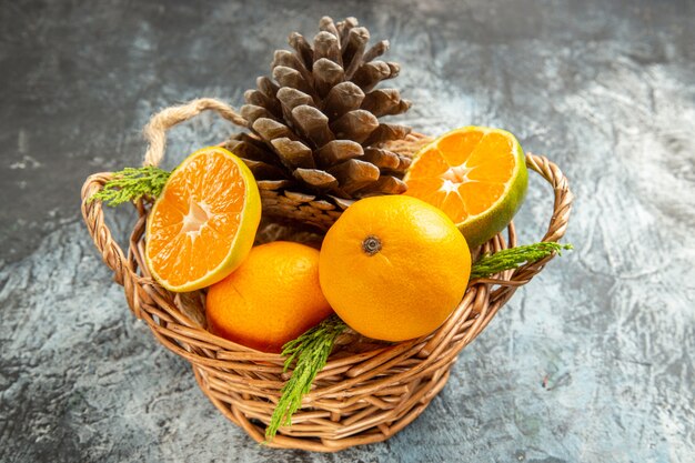 Vue de face de mandarines fraîches juteuses à l'intérieur du panier sur une table gris clair