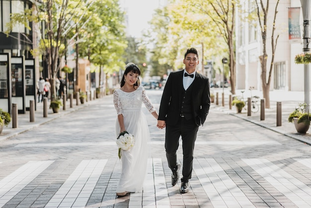 Vue de face de la mariée et le marié marchant dans la rue