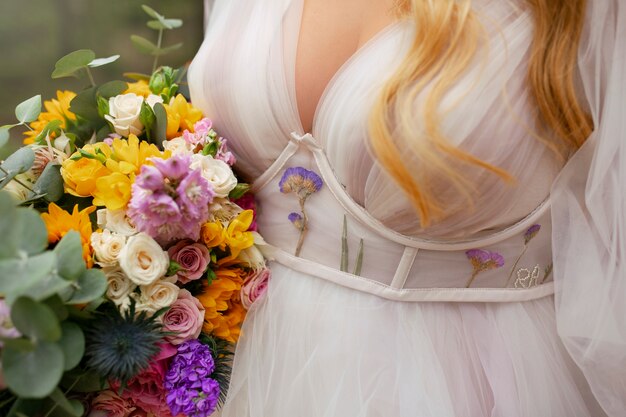 Photo gratuite vue de face mariée posant avec des fleurs