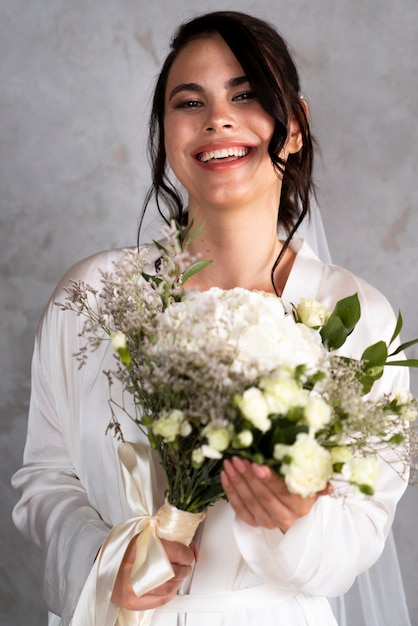 Vue de face mariée souriante tenant des fleurs