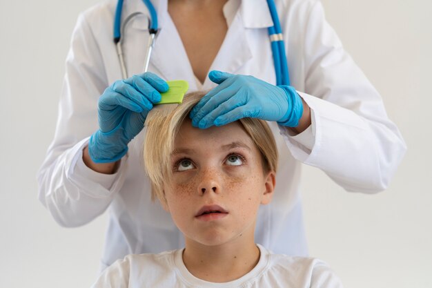 Vue de face médecin aidant un garçon avec des poux