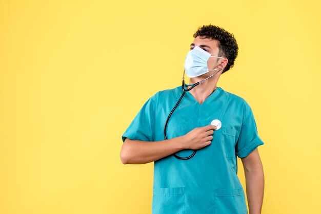 Vue de face médecin le médecin en masque vérifie son cœur