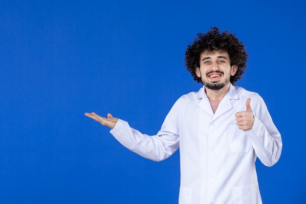 Vue de face d'un médecin de sexe masculin en costume médical sur fond bleu hôpital de vaccin contre le virus covid- pandémie de médecine médicamenteuse contre le coronavirus