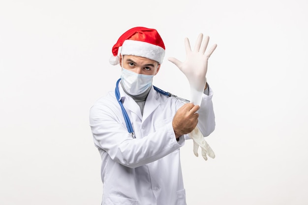 Vue de face d'un médecin de sexe masculin portant des gants sur un mur blanc