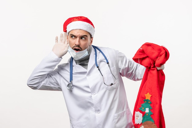 Vue de face d'un médecin de sexe masculin avec un sac présent sur un mur blanc