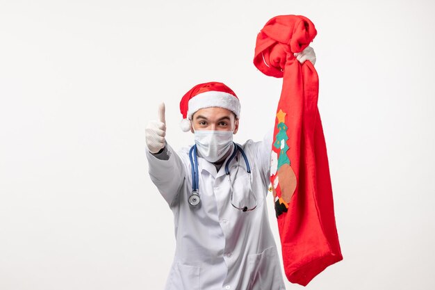 Vue de face d'un médecin de sexe masculin avec un sac présent sur un mur blanc