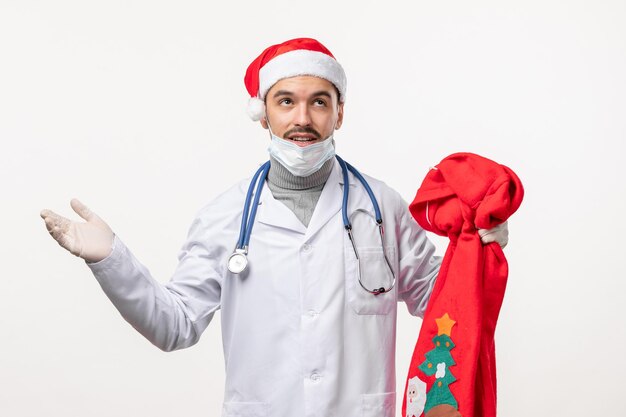 Vue de face d'un médecin de sexe masculin avec un sac présent sur un mur blanc