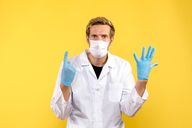 Vue de face médecin de sexe masculin surpris sur fond jaune maladie médicale pandemic covid-
