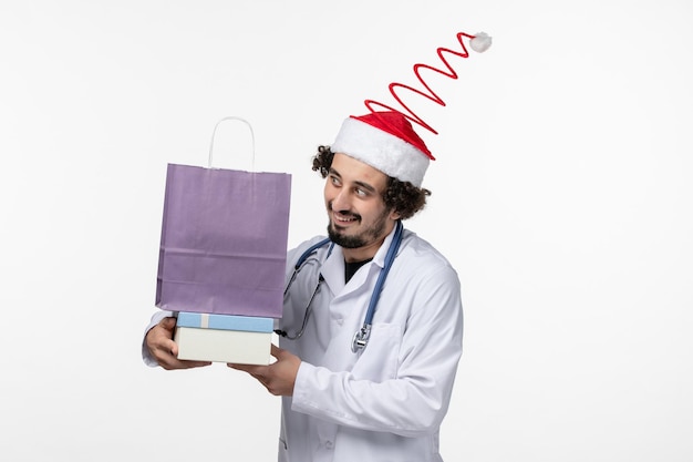 Vue de face d'un médecin de sexe masculin tenant des cadeaux sur un mur blanc